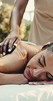 Hands, woman and back massage at spa with hot stone, deep tissue and treatment for self care. Masseuse, mature person and detox at salon with warm rocks, healing and thermal therapy for body wellness