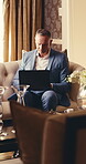 Businessman, hotel and typing with laptop on sofa for remote work, schedule travel or accommodation. Man, traveler or freelancer with computer or technology for business opportunity in luxury lodge