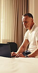 Remote work, typing and man with laptop in hotel, online and research for story development on web. Travel, senior writer and happy person with technology, freelancer and editing article in bedroom