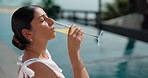 Holiday, relax and woman at swimming pool with drink, stress relief or chill by water in summer. Poolside, cocktail and female person on vacation at luxury resort, travel or refreshing mimosa outdoor