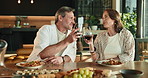 Couple, cheers and dining with wine glass for romantic date, dinner or meal together in home. Man, woman or toast with alcohol, food or drink for honeymoon celebration, event or holiday in house