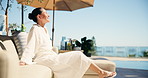 Thinking, woman and relax at resort with smile, enjoy sunshine and daydreaming on summer holiday. Thoughts, mature person and unwind on couch with mindset, calm morning and vacation at accommodation