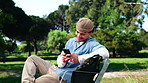 Text, laugh and college student on park bench with phone, online chat and funny post on social media. Digital, humor and happy man outdoor with tech, university meme and comic reaction on gen z blog.