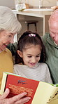 Happy, grandparents and reading book in home with child, learn knowledge and visit for weekend break. Senior people, girl or grandchild in living room with fairytale novel, talk and bonding together.