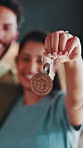 Hand, key and couple moving in new house with security, property investment and support for purchase. Face, happy married people and goals in dream home with keychain, safety and relocation together.