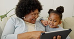 Happy, grandmother and child reading in house with tablet, conversation and ebook for fairytale. Senior black woman, grandchild and talk in home with tech, bonding and storytelling for development.