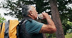 Hiking, break and old man drinking water in nature with adventure, thinking and retirement wellness. Active, senior person and reflection outdoor in forest with trekking journey, hydration or fitness