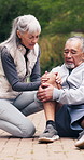 Senior, couple or knee pain with help for fitness, workout accident or fall on outdoor concrete. Active, elderly man and woman with sore leg or injury for muscle tension, sprain or discomfort in park