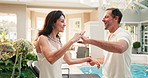 Couple, dance and holding hands at resort with smile, romance and support on anniversary getaway. Happy, mature people or laugh at retreat for celebration, rhythm and romantic partner for holiday fun