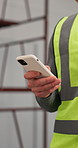 Person, architect or hands with phone in construction site for online app or mobile surveillance. Contractor, civil engineer or typing on technology for security control or monitoring building safety