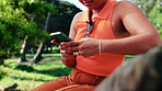 Woman, hands and relax in park with phone, typing text message and scroll website for digital news. Person, outdoor and chill on bench with tech, browsing social media and search for blog article.