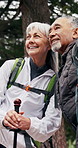 Senior, hiking and happy couple in nature for sightseeing, outdoor adventure or journey together. Active, elderly man and woman with smile or walking stick for trekking, fitness or travel in forest