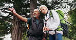 Hiking, adventure and old couple talk in nature with smile, trip or explore together for retirement. Happy, senior people and point outdoor in woods with trekking, fitness or interracial relationship