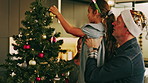 Family, bauble and Christmas tree in home for decor, festive celebration or bonding together. Mom, dad or child with ornament, applause or thank you for December holiday, weekend or good job in house