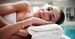 Woman, face and relax in resort with peace, comfort and rest on towel for stress relief at spa. Smile, client and mature person on wellness retreat for skincare, self care and bed at luxury hotel