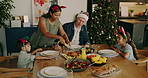 Christmas, family and dishing food with children for festive celebration or dining together. Mom, dad and kids with meal preparation for eating or December holiday gathering on dinner table in house