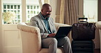 Laptop, luggage and business man at hotel lobby for remote work, travel and internet connection. Mature, black person and typing on computer for freelance job, accomodation check in and schedule