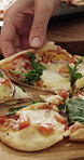 Hands, person and eating pizza in home for lunch, homemade meal and vegan toppings with friends. Vegetarian slice, cheese and hungry for food with nutrition, health or dinner on wooden counter