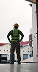 Back, man and construction worker on site with thinking, planning or vision for property development. Builder, person and reflection outdoor by building with infrastructure decision, PPE and safety.