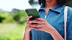 Woman, hands and relax in nature with phone, typing text message and check website for digital news. Person, outdoor and chill in park with tech, browsing social media and search for blog article.