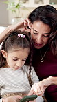 Mom, kid and play in house with phone, conversation and help with video game for child development. Happy, woman and daughter talk on sofa with tech, swipe and mobile gaming for knowledge growth.