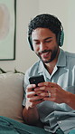 Headphones, happy and man with phone on sofa for streaming song, audio and create playlist. House, relax and person with cellphone for radio, track and listening with music subscription on weekend