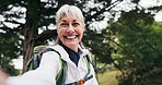 Face, selfie and old woman hiking in nature with backpack, recording video or memories of adventure. Happy, senior person and journey outdoor in forest with social media vlog, photography or wellness