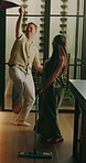 Cleaning, dance and couple with music in kitchen for chores, housekeeping and hygiene on weekend. Marriage, love and man with woman with spray bottle, mop and cloth for maintenance, fun and bonding