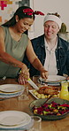 Christmas, mother or father with cutting feast, house bonding or roast in festive celebration. Xmas, seasonal or interracial family in home with meal, happy moment or connection at holiday table.