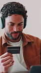 Laptop, credit card and man in home with headphones, music membership and streaming service renewal. Debit, internet banking and happy person with tech for payment, subscription or audio discount
