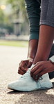 Hands, shoes and tying with laces in nature for outdoor workout preparation, safety or security. Active, person or runner getting ready with sneakers on road for fitness exercise, health or wellness