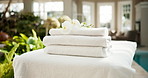 Empty, spa and towel on bed with flower, guest arrival and welcome experience for hospitality. Massage, table or fresh linen at resort with floral decor, complimentary service and luxury housekeeping