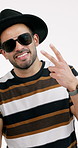 Fashion, casual and man with peace sign, sunglasses and style confidence with basic aesthetic. Face, clothes and happy person on studio background with emoji, eyewear and fedora in effortless outfit.