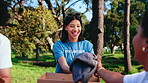 Volunteer, woman or team in park with clothes, supply pack or inventory sorting in charity program. Happy, people or NGO with garment box, distribution management or group support in outreach project