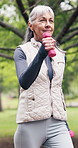 Senior, walking or happy woman with dumbbells in nature for outdoor workout, fitness or exercise. Active, elderly or female person with smile or weightlifting for cardio, strength or mobility in park